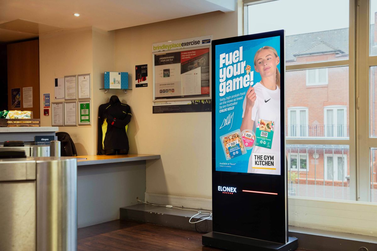 A portrait digital screen inside a gym reception
