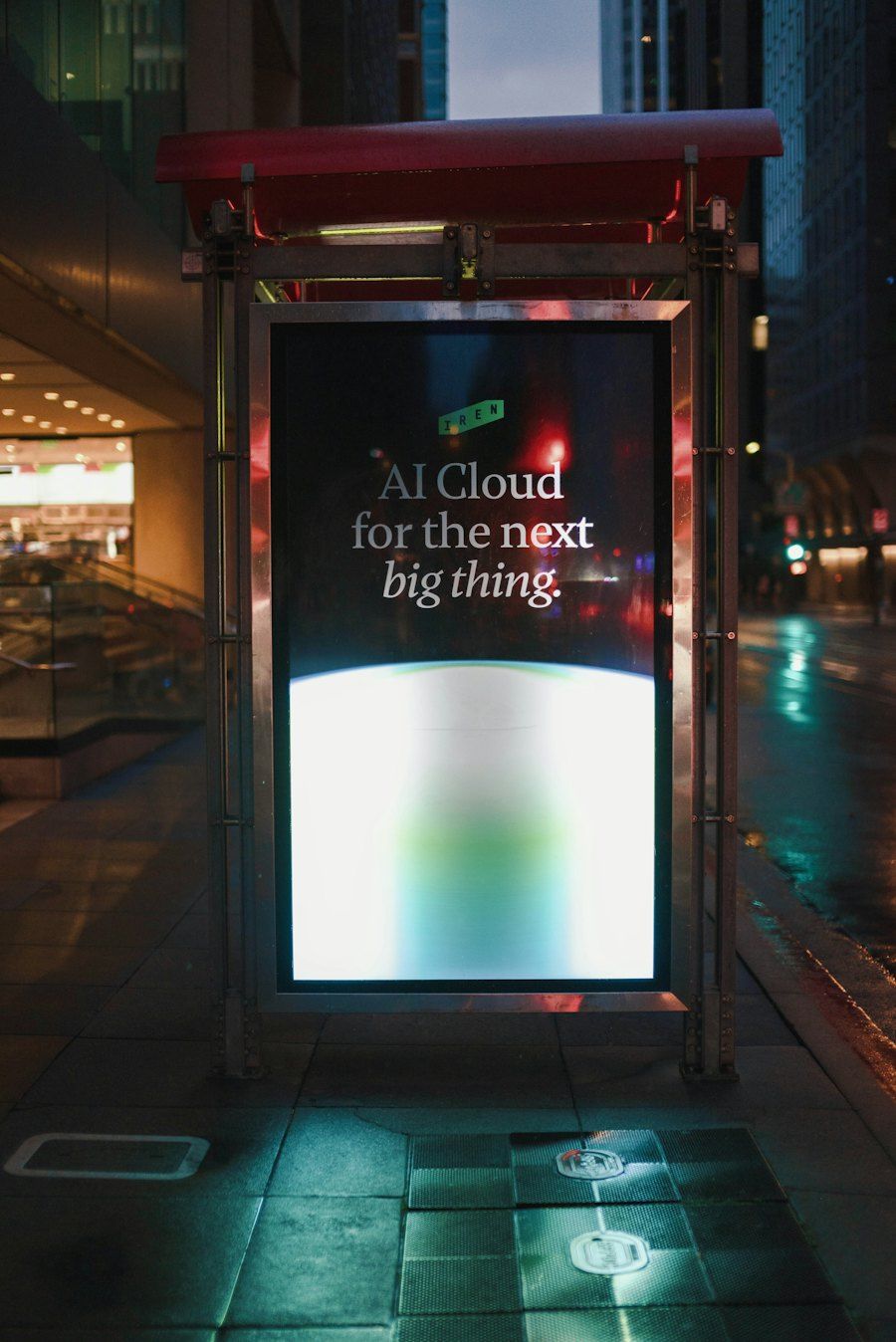 A digital street screen at a bus stop at night