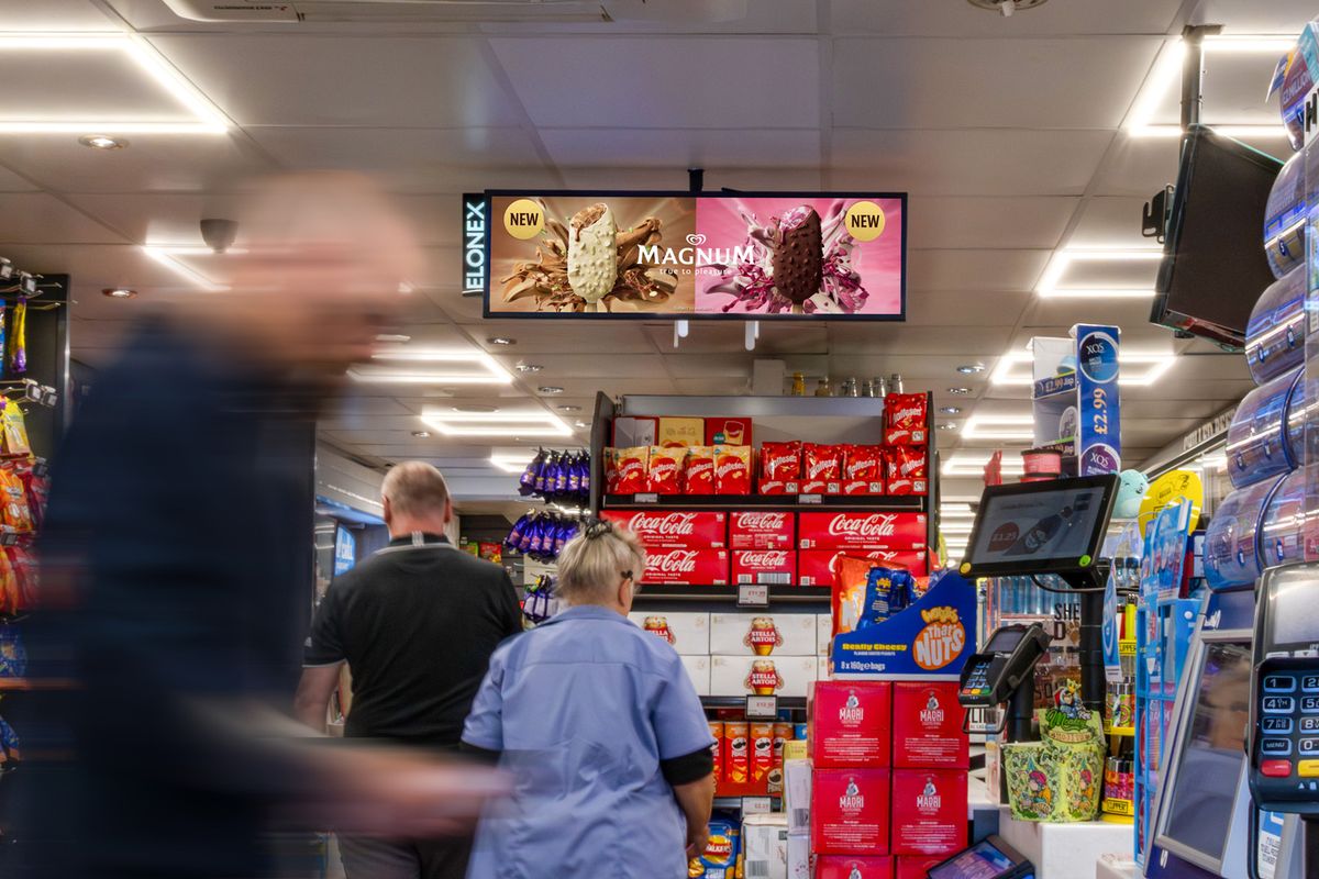 Digital screens above the counter in a busy convenience store