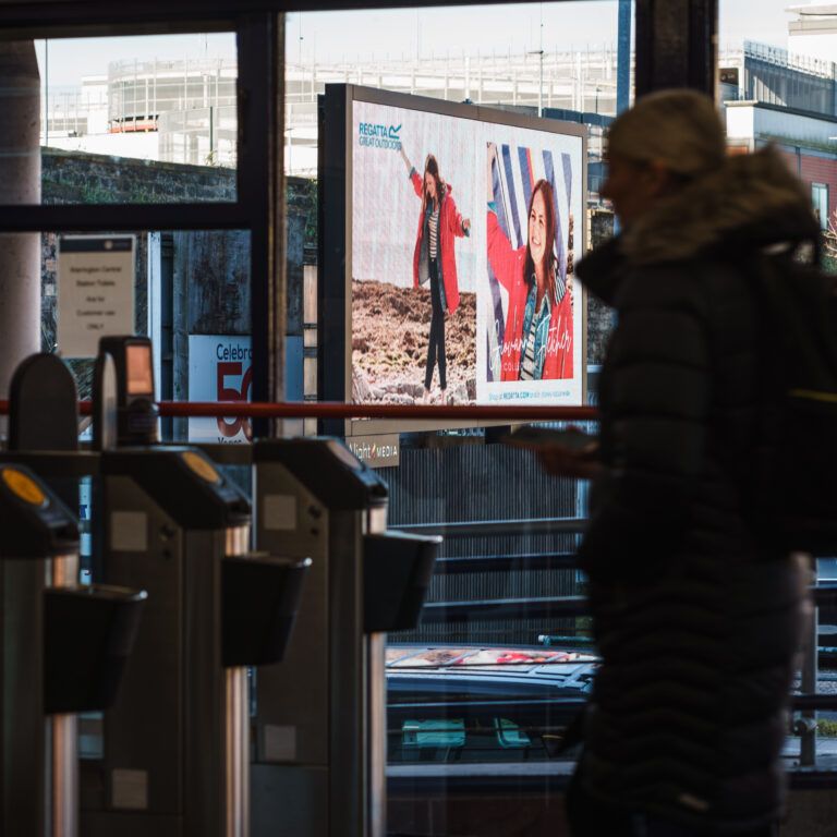 A digital billboard seen from inside a railway station